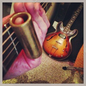 Brass slide on Guild guitar neck with mid-60's Gibson 125 on the floor.